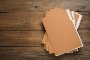 Yellow files with documents on wooden table, top view